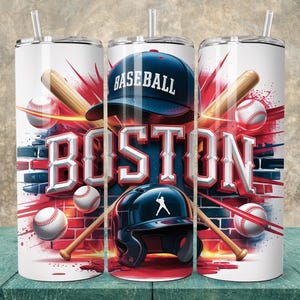 Pode incluir: Um copo branco com um design de beisebol, exibindo a palavra "BOSTON" em letras grandes. O design incorpora bolas de beisebol, bastões, um boné de beisebol e um capacete, tudo em um fundo de parede de tijolos. O copo tem um canudo.