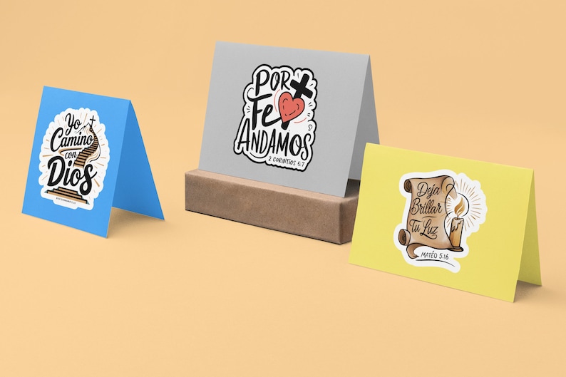 Peut inclure: Trois cartes de v&oelig;ux avec des citations religieuses et des illustrations. La premi&egrave;re carte est bleue et repr&eacute;sente un escalier avec le texte "Yo Camino con Dios". La deuxi&egrave;me carte est grise et repr&eacute;sente un c&oelig;ur avec une croix et le texte "Por Fe Andamos 2 Corintios 5:7". La troisi&egrave;me carte est jaune et repr&eacute;sente une bougie avec le texte "Deja Brillar Tu Luz Mateo 5:16".