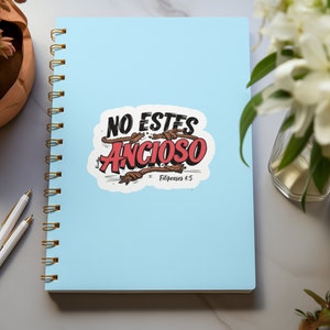 Peut inclure: Un carnet &agrave; spirales bleu avec un autocollant blanc qui dit "NO ESTES ANSIOSO" en lettres rouges et noires avec des accents de corde brune. L'autocollant comprend &eacute;galement le texte "Philippiens 4:5".