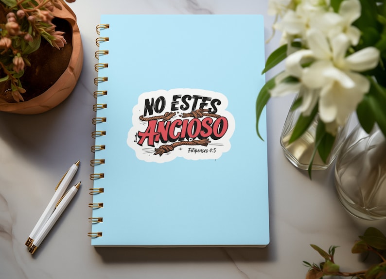 Peut inclure: Un carnet &agrave; spirales bleu avec un autocollant blanc qui dit "NO ESTES ANSIOSO" en lettres rouges et noires avec des accents de corde brune. L'autocollant comprend &eacute;galement le texte "Philippiens 4:5".