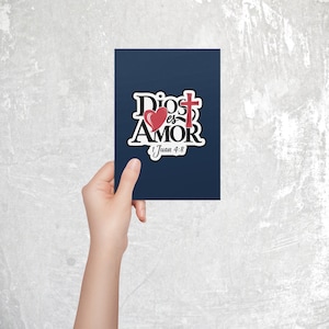 Peut inclure: Une carte bleue avec un autocollant blanc qui dit "Dios es Amor" avec un c&oelig;ur rouge et une croix rouge. L'autocollant dit aussi "1 Juan 4:8".