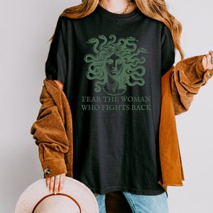 May include: Black t-shirt with a green graphic of Medusa's head with snakes and the text "Fear the woman who fights back."