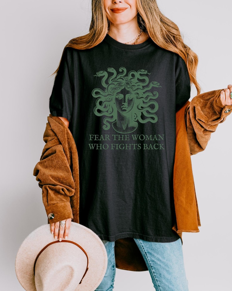 May include: Black t-shirt with a green graphic of Medusa's head with snakes and the text "Fear the woman who fights back."