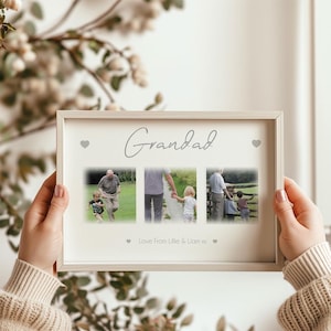 May include: A framed photo collage with the word "Grandad" in cursive script. The collage features three photos and the text "Love From Lillie & Liam xx". The frame is light-colored and rectangular, with small heart accents.