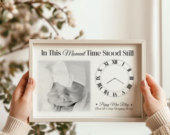 Può includere: Stampa fotografica in bianco e nero incorniciata con la scritta "In This Moment Time Stood Still". La stampa include una foto del bambino, un grafico dell'orologio e i dettagli della nascita. La cornice è di colore chiaro.