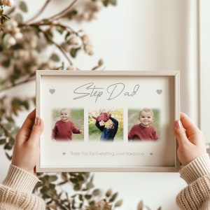 May include: A framed photo collage with the words "Step Dad" in cursive script. The collage features three photos of a child and a man. The bottom of the frame reads "Thank You For Everything, Love Harrison xx". The frame is held by a person.
