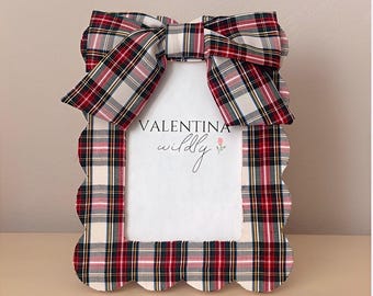 May include: A decorative picture frame with a plaid pattern in red, white, and black. The frame has a scalloped edge and a large bow at the top. The text "VALENTINA wildly" is visible on the white insert.