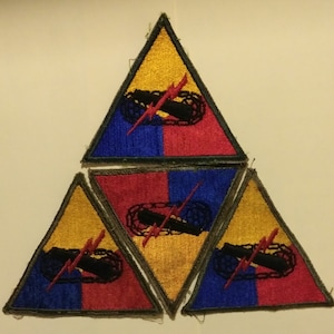 May include: Three triangular patches with a yellow, red, and blue design. The patches feature a black and white image of a cannon with a lightning bolt and a chain.
