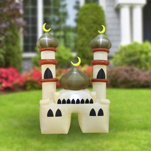 May include: An inflatable white mosque with green and brown accents. The mosque has three domes and two minarets. The mosque is lit up with white lights.