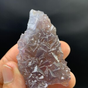 K&ouml;nnte beinhalten: Ein nat&uuml;rliches, rohes Fluorite-Kristall-Exemplar. Der Kristall weist eine komplexe Anordnung kubischer Formationen in Lila- und Braunt&ouml;nen auf. Die raue Textur und die einzigartige Form unterstreichen seine nat&uuml;rliche Sch&ouml;nheit.