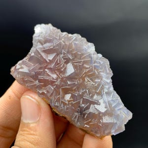 K&ouml;nnte beinhalten: Nahaufnahme einer nat&uuml;rlichen Fluorit-Mineralprobe. Der Fluorit hat eine kristalline Struktur mit einer Mischung aus lila und klaren Farben. Die Kanten des Fluorits sind hellbraun.