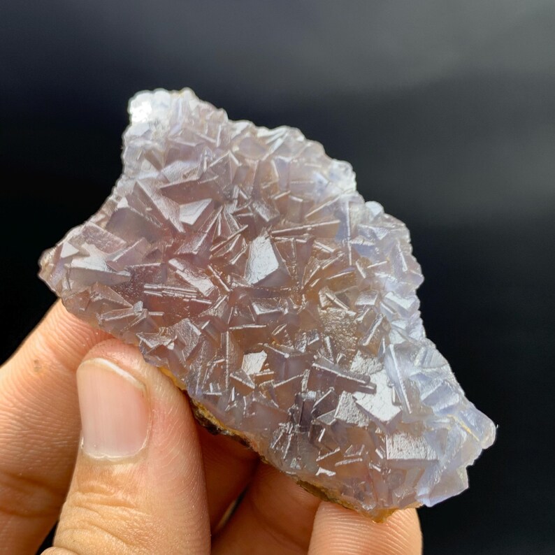 K&ouml;nnte beinhalten: Nahaufnahme einer nat&uuml;rlichen Fluorit-Mineralprobe. Der Fluorit hat eine kristalline Struktur mit einer Mischung aus lila und klaren Farben. Die Kanten des Fluorits sind hellbraun.