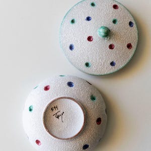 May include: A white ceramic bowl and lid set with a textured surface and colourful polka dots. The dots are red, blue, and green. The lid has a small green knob. The bottom of the bowl has the text "511" and "Italy".