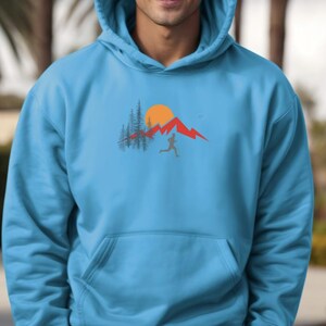 May include: A light blue hoodie with a graphic of a person running in front of a mountain range with a sun and trees.