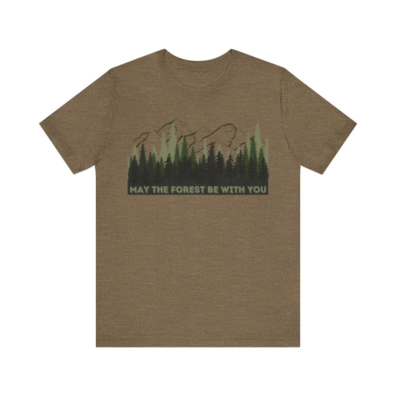 May include: A brown t-shirt with a green and brown mountain and forest graphic. The text "May the forest be with you" is printed below the graphic.