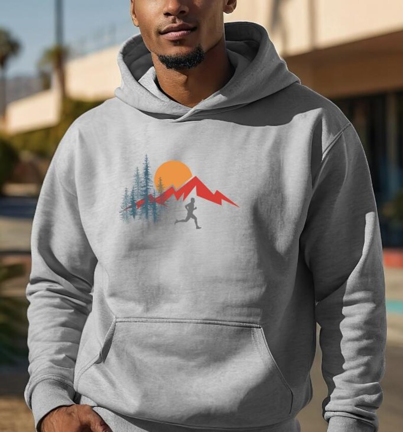 May include: A gray hooded sweatshirt with a graphic design of a person running in front of a mountain range with a sun and trees.