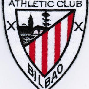 May include: White and red athletic club patch with the text "Athletic Club Bilbao" and a black and white image of a building and tree.