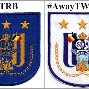 Può includere: Due toppe ricamate, una blu e una bianca, con uno stemma che presenta una corona, stelle e le lettere "SCA". La toppa blu ha il testo "#HomeTRB" e la toppa bianca ha il testo "#AwayTW".