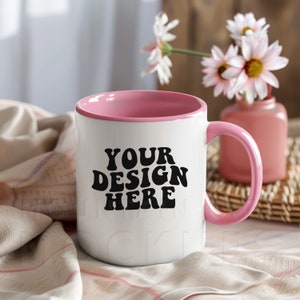 Puede incluir: Taza de cerámica blanca con borde y asa de color rosa. La taza tiene el texto "YOUR DESIGN HERE" en letras negras.