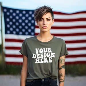 May include: A woman wearing a green t-shirt with the text "YOUR DESIGN HERE" in white. She is standing in front of an American flag.