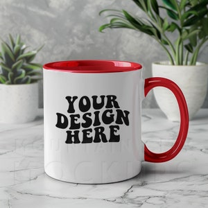 Puede incluir: Taza de cerámica blanca con borde y asa rojos. La taza tiene el texto "YOUR DESIGN HERE" en negro.