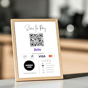 Könnte beinhalten: Ein weißes Schild mit einem Holzrahmen, das einen QR-Code für kontaktloses Bezahlen anzeigt. Das Schild enthält auch den Text "Scan to Pay", "Zelle", "Auch akzeptiert" und Logos für VISA und Mastercard. Das Schild enthält außerdem ein Firmenlogo, den Firmennamen und Kontaktinformationen.
