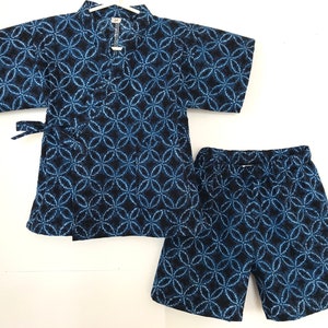 Könnte beinhalten: Ein zweiteiliges Set im japanischen Stil, bestehend aus einem kurzärmeligen Oberteil und passenden Shorts. Der marineblaue Stoff ist mit einem sich wiederholenden blau-weißen Blumenmuster versehen. Das Oberteil hat einen Wickelverschluss mit Bindeband.