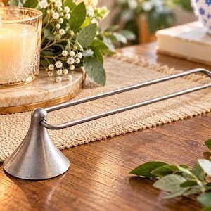 May include: A silver-toned metal towel bar featuring a conical base and a long, slender, rounded rectangular loop. The finish has a slightly weathered, matte texture, and the design is composed of a single continuous piece of metal.
