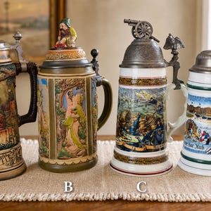 以下が含まれることがあります： A、B、C、Dとラベル付けされた4つの装飾的な陶器製ビールジョッキ。ジョッキAはテキスト付きの酒場のシーン。Bはノームの蓋と庭の人物。Cは大砲の蓋と戦闘シーン。Dは都市の風景が描かれています。