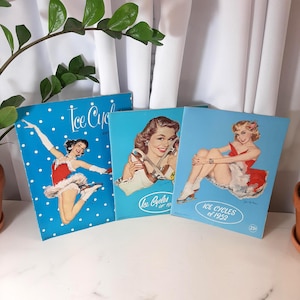 May include: Three vintage Ice Cycles of 1952 promotional cards featuring illustrations of women in red and white skating outfits on a blue background. The cards have the text "Ice Cycles of 1952" printed on them.