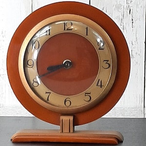 May include: A white ceramic mug with a black handle and the text "But First, Coffee" in a bold, black font. The mug is set against a blurred background, suggesting a cosy setting.