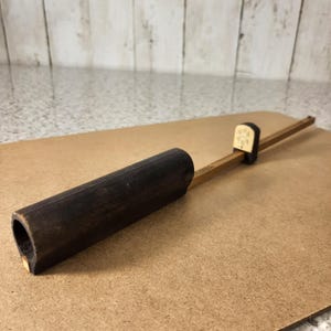 以下が含まれることがあります： 黒い持ち手と「But First, Coffee」のテキストが太字の黒で書かれた白いセラミックマグ。マグカップはぼやけた背景に置かれており、居心地の良い環境を示唆しています。