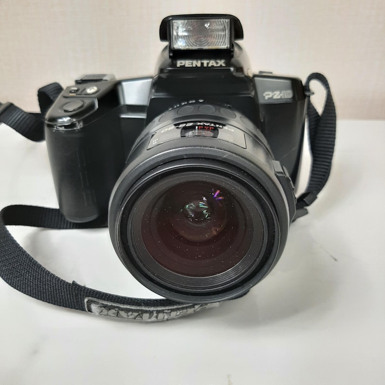 May include: A black Pentax PZ40 film camera with a built-in flash and a black lens.