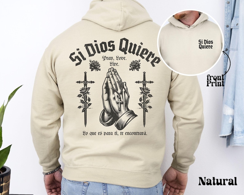 May include: A beige hoodie with a black print on the back that says "Si Dios Quiere" with a praying hands design and two swords. The front of the hoodie has a smaller print that says "Si Dios Quiere".
