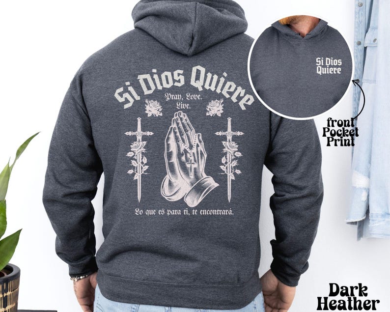 May include: Dark heather grey hoodie with a large graphic print on the back that says "Si Dios Quiere" with praying hands, roses, and swords. The front pocket has a smaller print that says "Si Dios Quiere".