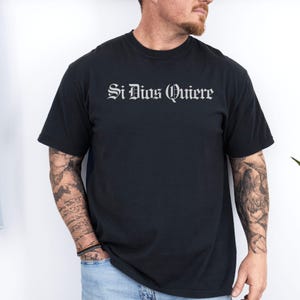 Si Dios Quiere” in Old English font on a Comfort Colors tee. Spanish for “if God wills it.” A humble, faith-filled expression often used in prayer, hope, and daily life. Soft vintage wash cotton.