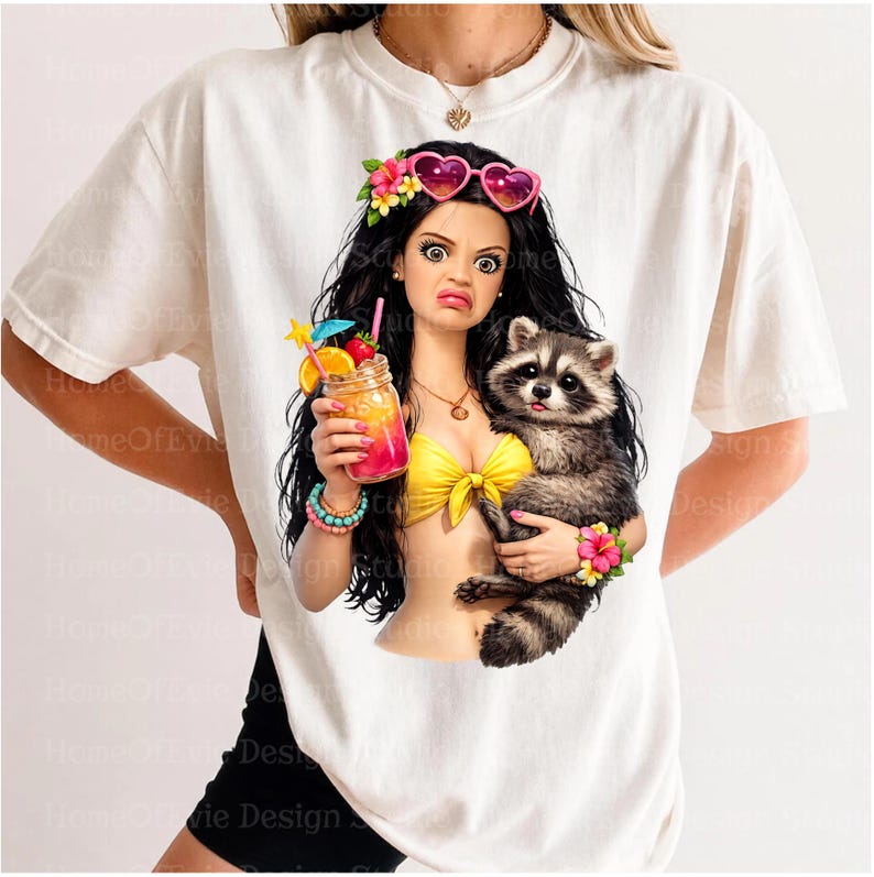 May include: A white t-shirt featuring a graphic of a character with long black hair wearing heart-shaped pink sunglasses and a yellow bikini top. The character holds a colorful tropical drink and a raccoon, both adorned with bright floral accents.