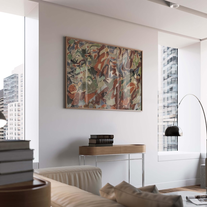 May include: Abstract art print in a wooden frame. The artwork features a mix of colors, including red, green, and brown. The print hangs on a white wall above a wooden console table with a stack of books.