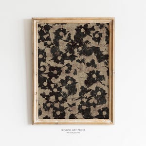 May include: A framed print with a black and brown abstract floral pattern. The print is in a light wood frame.