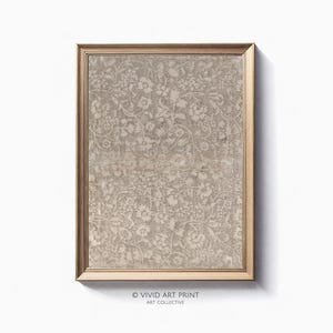 Pode incluir: Uma impressão emoldurada de um padrão floral vintage em tons de bege e branco. A impressão está em uma moldura simples de cor dourada.