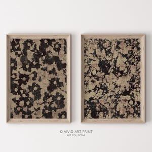 May include: Two framed abstract art prints with a black and white floral pattern on a beige background. The prints are in wooden frames.