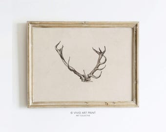 May include: A framed print of a black and white illustration of a deer antler. The frame is a light wood color and the print is on a beige background. The text "VIVID ART PRINT ART COLLECTIVE" is at the bottom of the print.