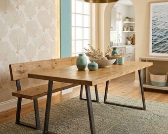 May include: A rectangular wooden dining table with a matching backless bench, both featuring natural wood grain surfaces and black metal U-shaped legs. The table is set with two light blue ceramic vases and a large bowl filled with dried botanicals.