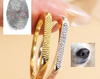 May include: Two thin metal rings, one gold-toned and one silver-toned. The gold ring features an engraved human fingerprint pattern, while the silver ring displays an engraved animal nose print pattern, matching the provided reference images.