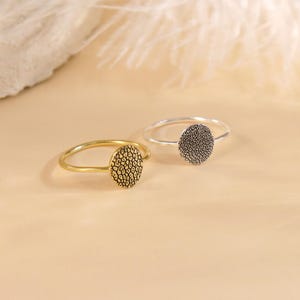 May include: Two simple rings with a textured, circular design. One ring is gold and the other is silver.