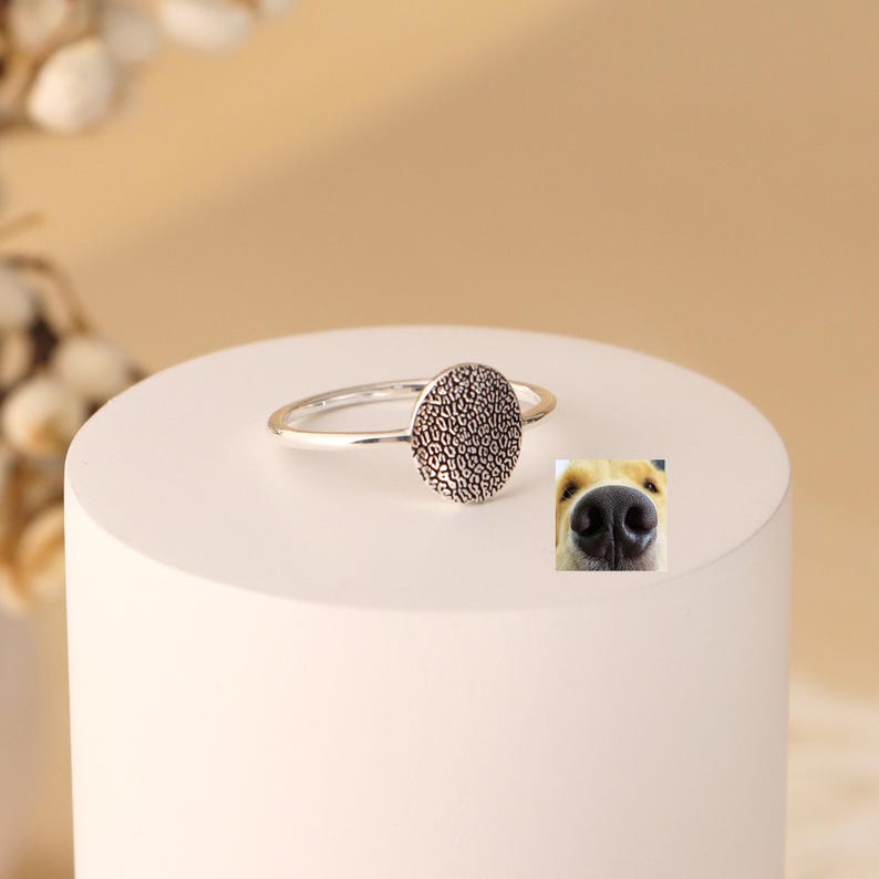 May include: A silver ring featuring a textured round disc. The disc has a pattern reminiscent of a dog's nose.