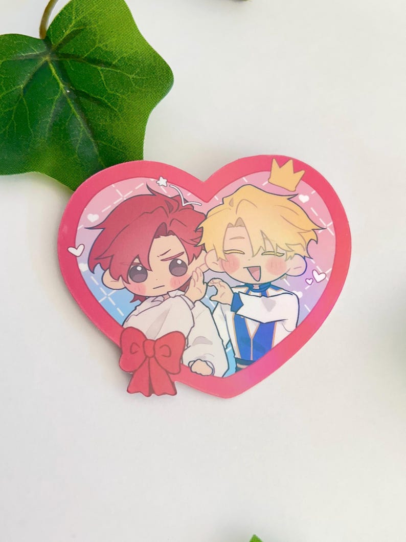 May include: A heart-shaped sticker with two cartoon characters. The character on the left has red hair and is wearing a white shirt with a red bow. The character on the right has blonde hair and is wearing a blue and white outfit with a crown. The sticker has a pink and blue background with white hearts.