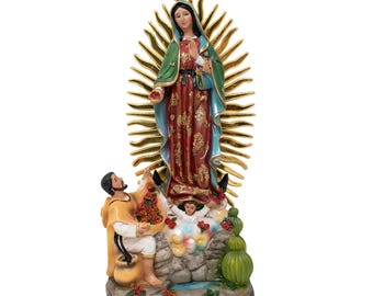 Puede incluir: Una figura de la Virgen María, Nuestra Señora de Guadalupe, de pie sobre una base rocosa con un hombre y un niño arrodillados ante ella. Lleva una túnica azul y roja con un halo dorado. El hombre lleva una cesta de flores.