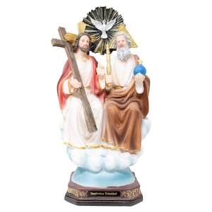 May include: A religious figurine depicting the Holy Trinity, featuring two figures seated on clouds above a base labeled Santisima Trinidad. One figure holds a wooden cross, the other a scepter and blue orb, with a white dove centered above.