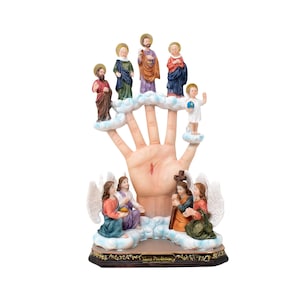 May include: A hand with a red mark on the palm, with figures of Jesus and the apostles on the fingers, and a scene of the crucifixion at the base. The figures are painted in bright colors and are surrounded by clouds. The base is decorated with a gold trim and the words "Mano Poderosa".